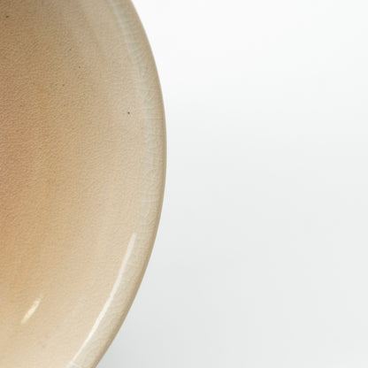 Detail of the Hagi Himetsuchi saucer's subtly speckled beige glaze and curved edge.