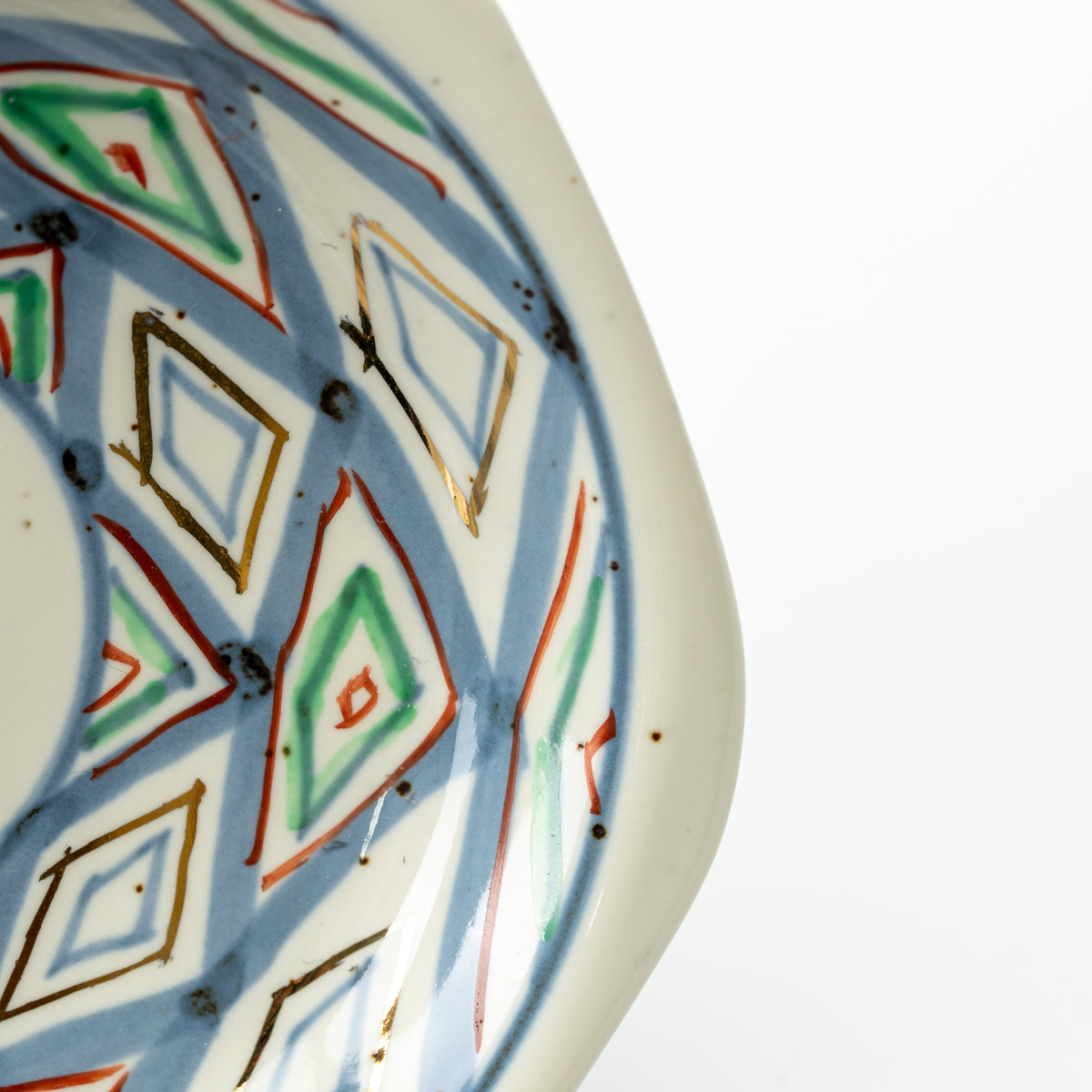 Close-up of the hexagonal saucer's blue, green and red diamond pattern and pale outer rim.