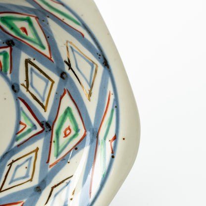 Close-up of the hexagonal saucer's blue, green and red diamond pattern and pale outer rim.