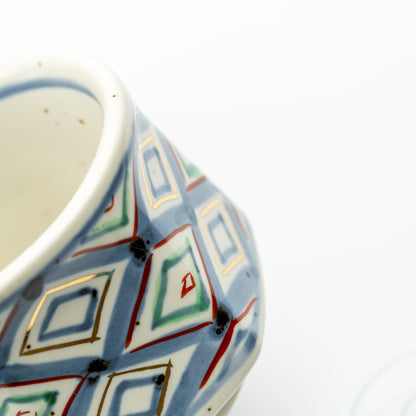 Detail of the demitasse cup's multicolored diamond pattern and blue line inside the rim.