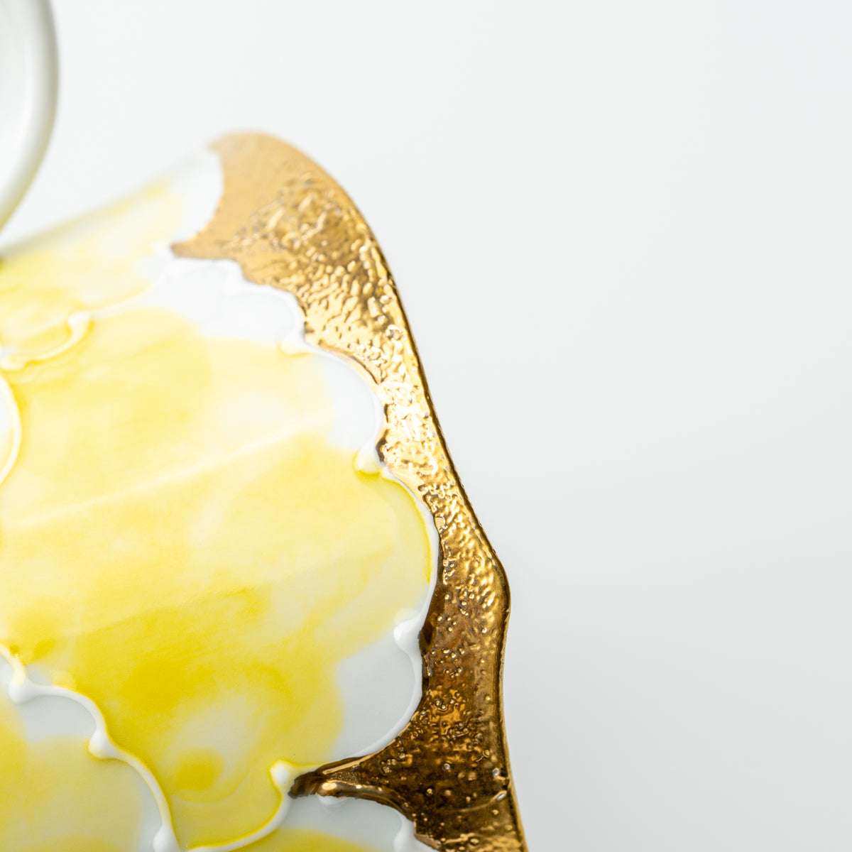 Close-up of a raised yellow peony and textured gold-colored decoration on the Bunzan mug.