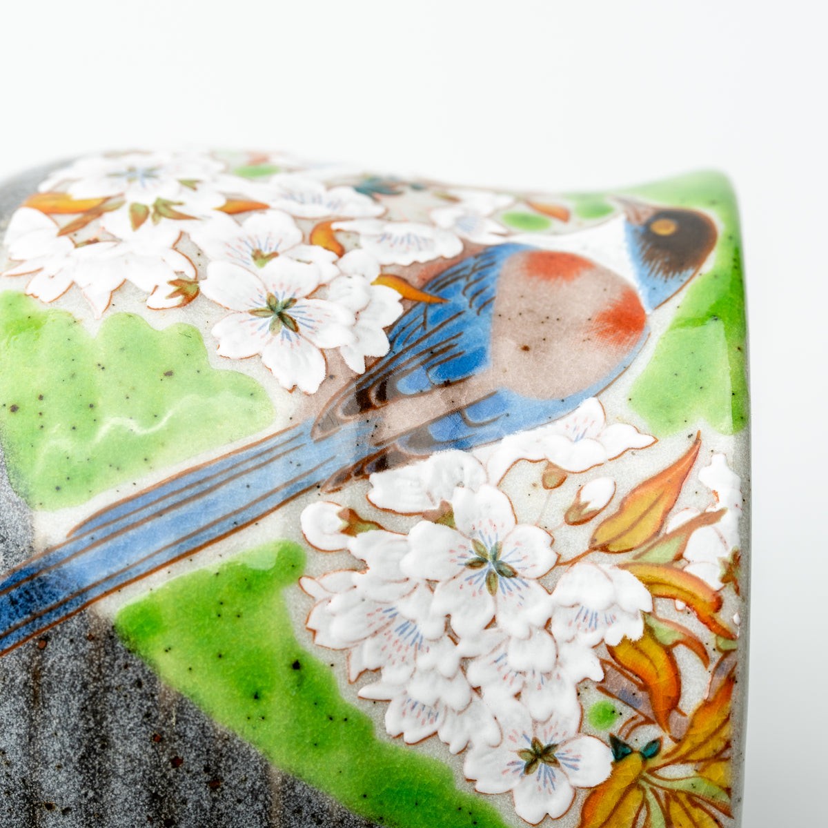 Close-up of a long-tailed bird and white cherry blossoms on the green-accented Kutani mug.