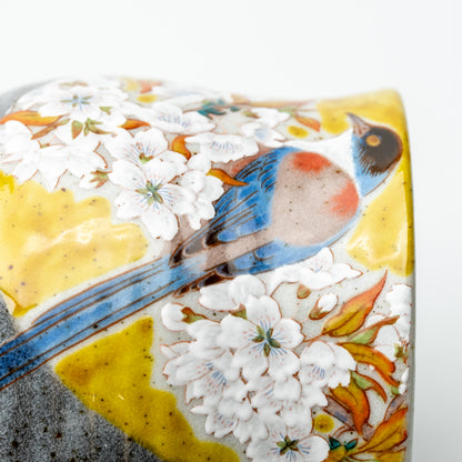 Close-up of a long-tailed bird and white cherry blossoms on the yellow-accented Kutani mug.