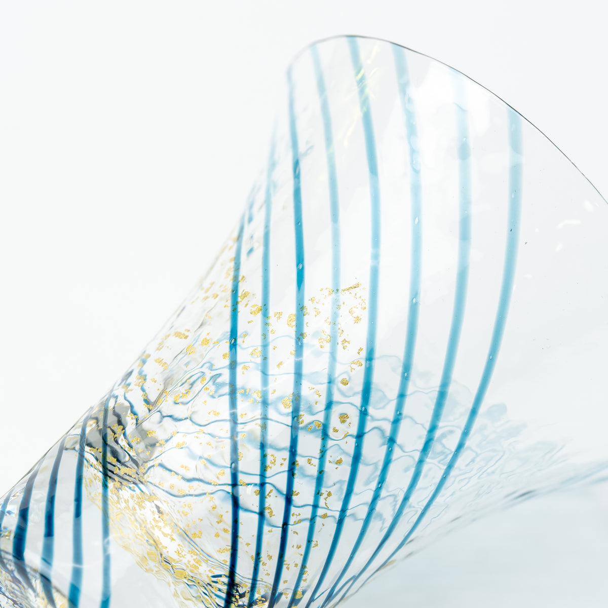 Close-up of blue curved lines and gold-colored flecks in the clear Yachiyo sake cup.