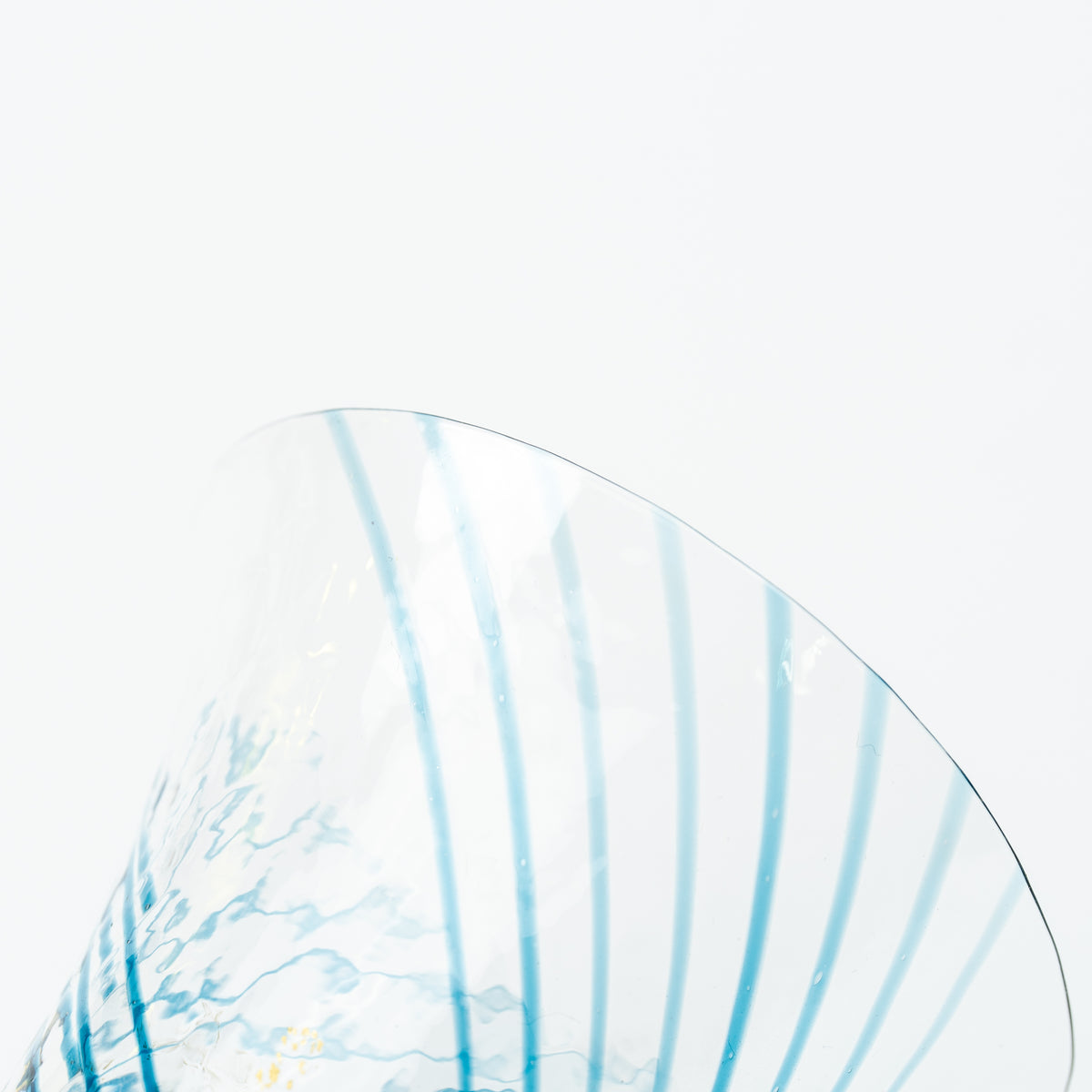 Detail of the flared rim and fine blue lines of the clear Yachiyo sake cup.