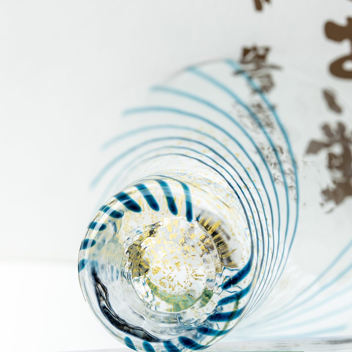 View into the Yachiyo sake cup showing curved blue stripes and gold-colored flecks at the bottom.