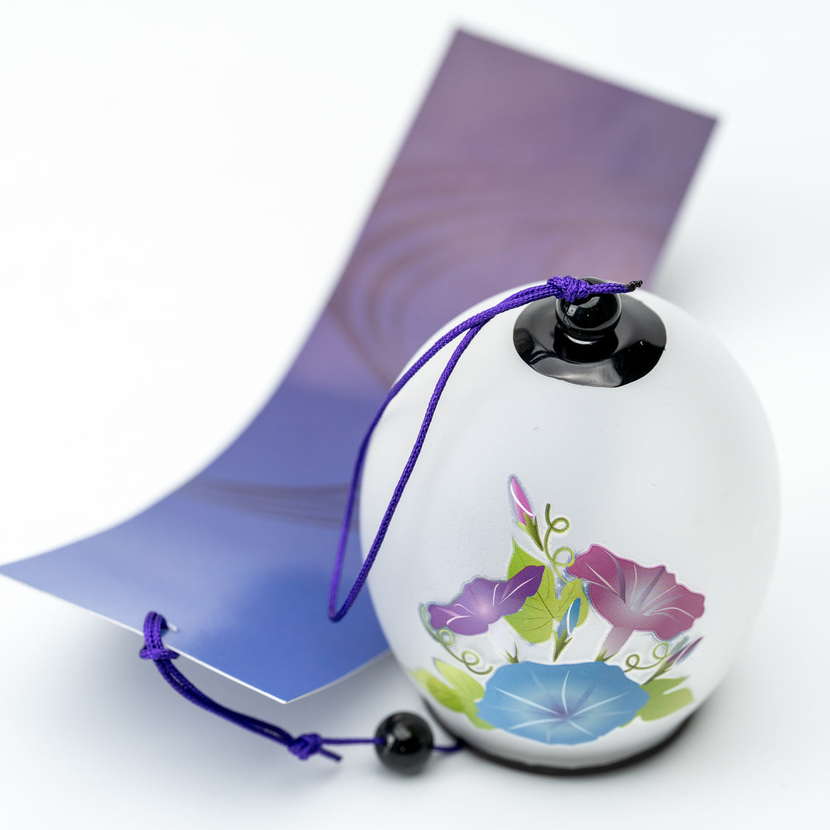 White morning glory wind chime with a purple cord and matching paper tag, shown upright.