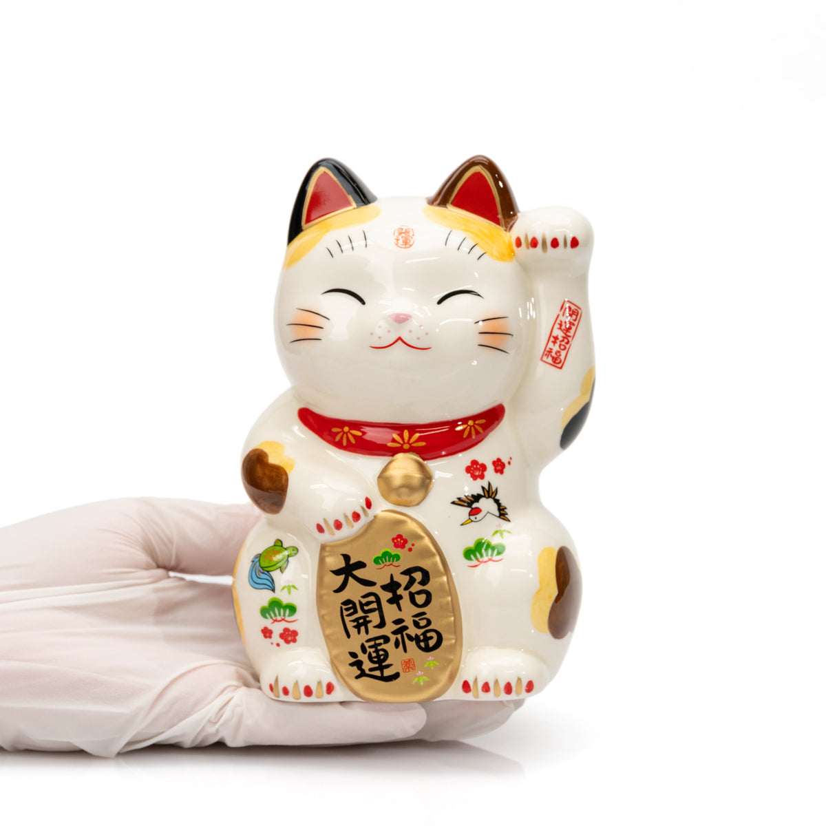 Large Yakushigama lucky cat held in a gloved hand for scale, showing its smiling face and raised paw.