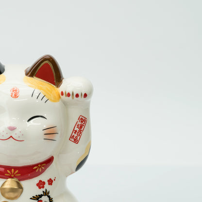 Close-up of the calico lucky cat's face and raised left paw