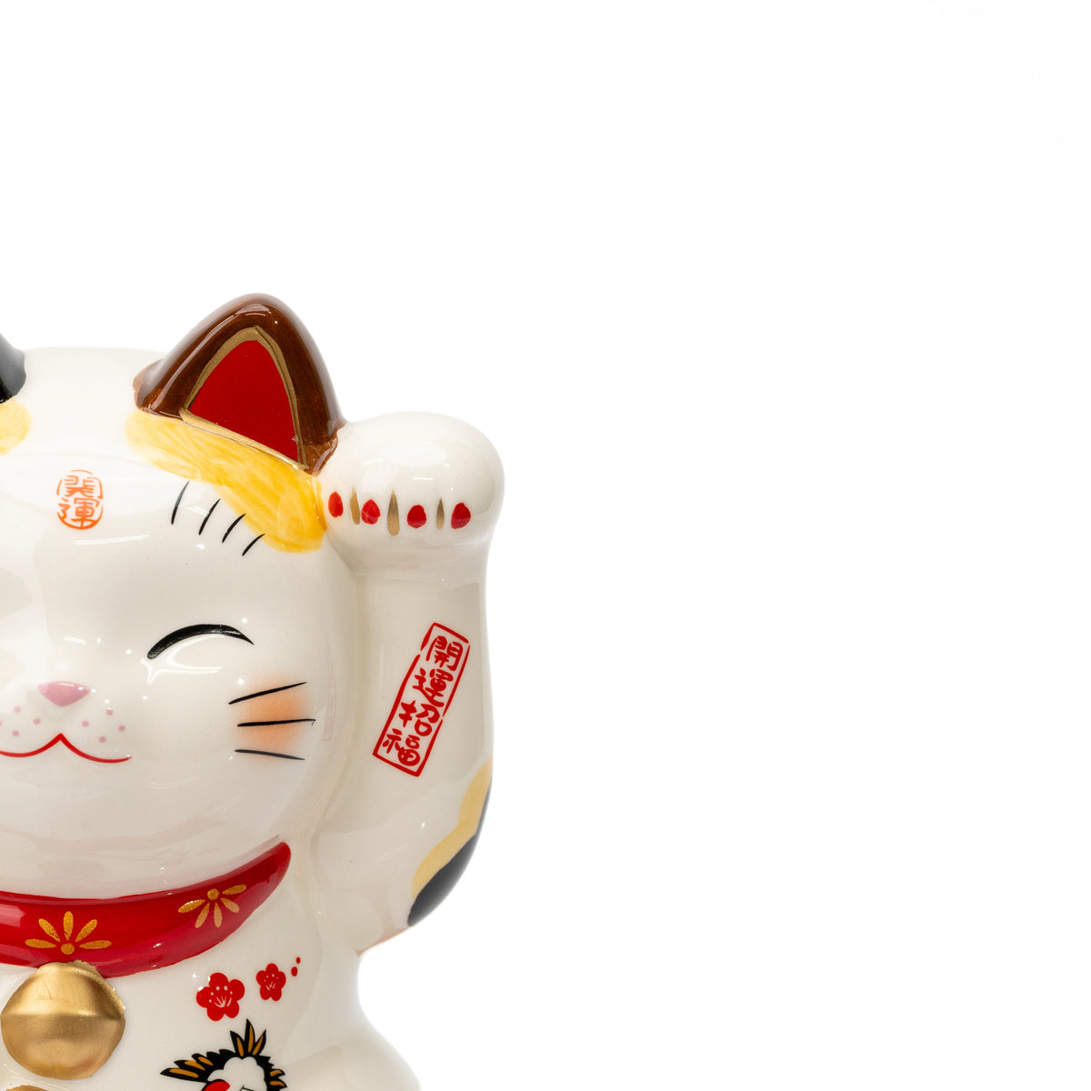 Close-up of a Yakushigama lucky cat's smiling face, raised paw and red markings.
