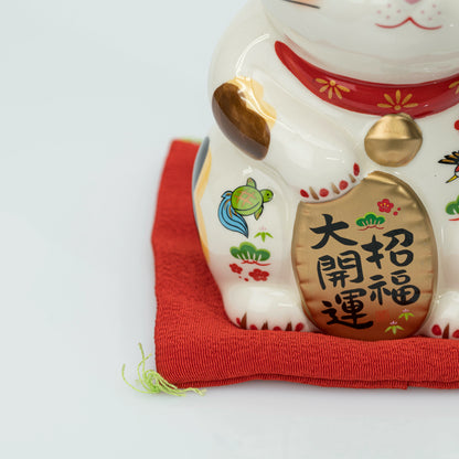 Close-up of the stationary lucky cat's gold coin and painted chest