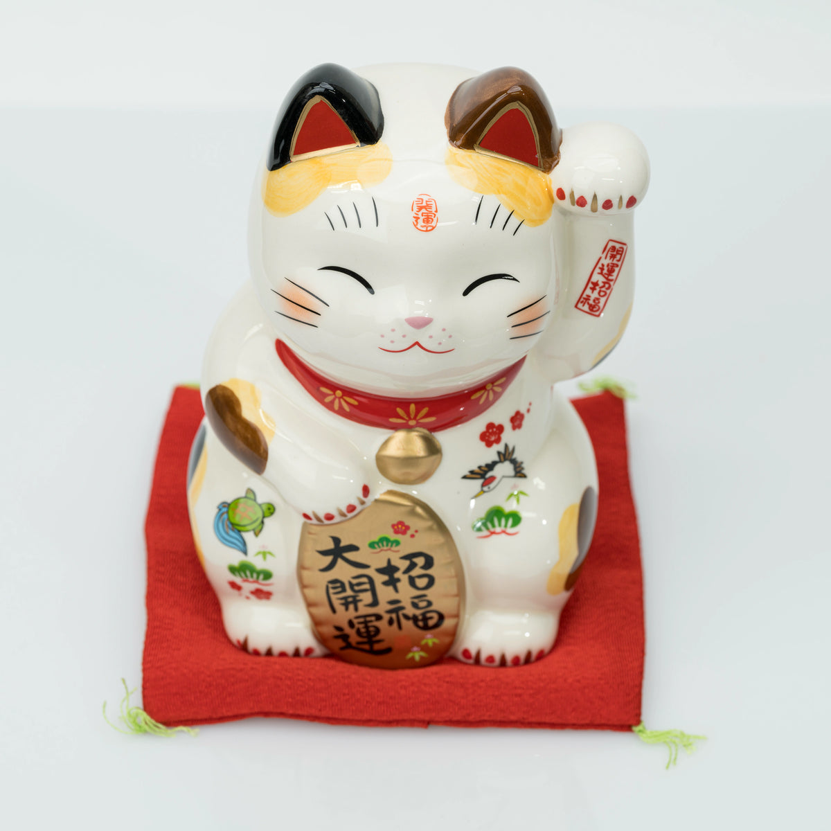 Upper front view of the stationary lucky cat with raised left paw