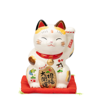 Front view of the large Yakushigama lucky cat on a red cushion with a gold-colored plaque and bell.