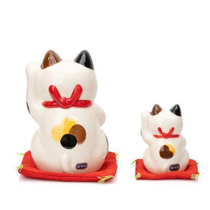 Rear view of the large and small Yakushigama lucky cats showing red bows and calico markings.