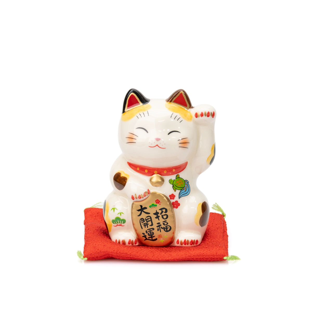 Front view of the small Yakushigama lucky cat with a raised paw, seated on a red cushion.