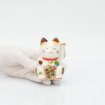 Small stationary calico lucky cat shown in a gloved hand