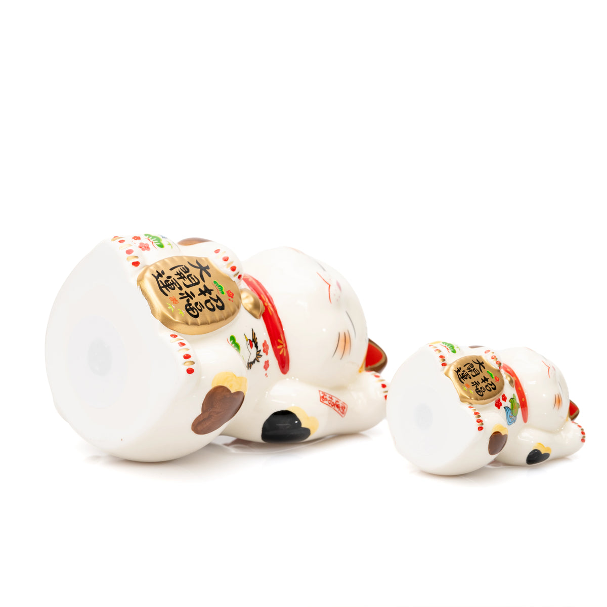 Large and small Yakushigama lucky cats lying on their sides to show their flat bases.