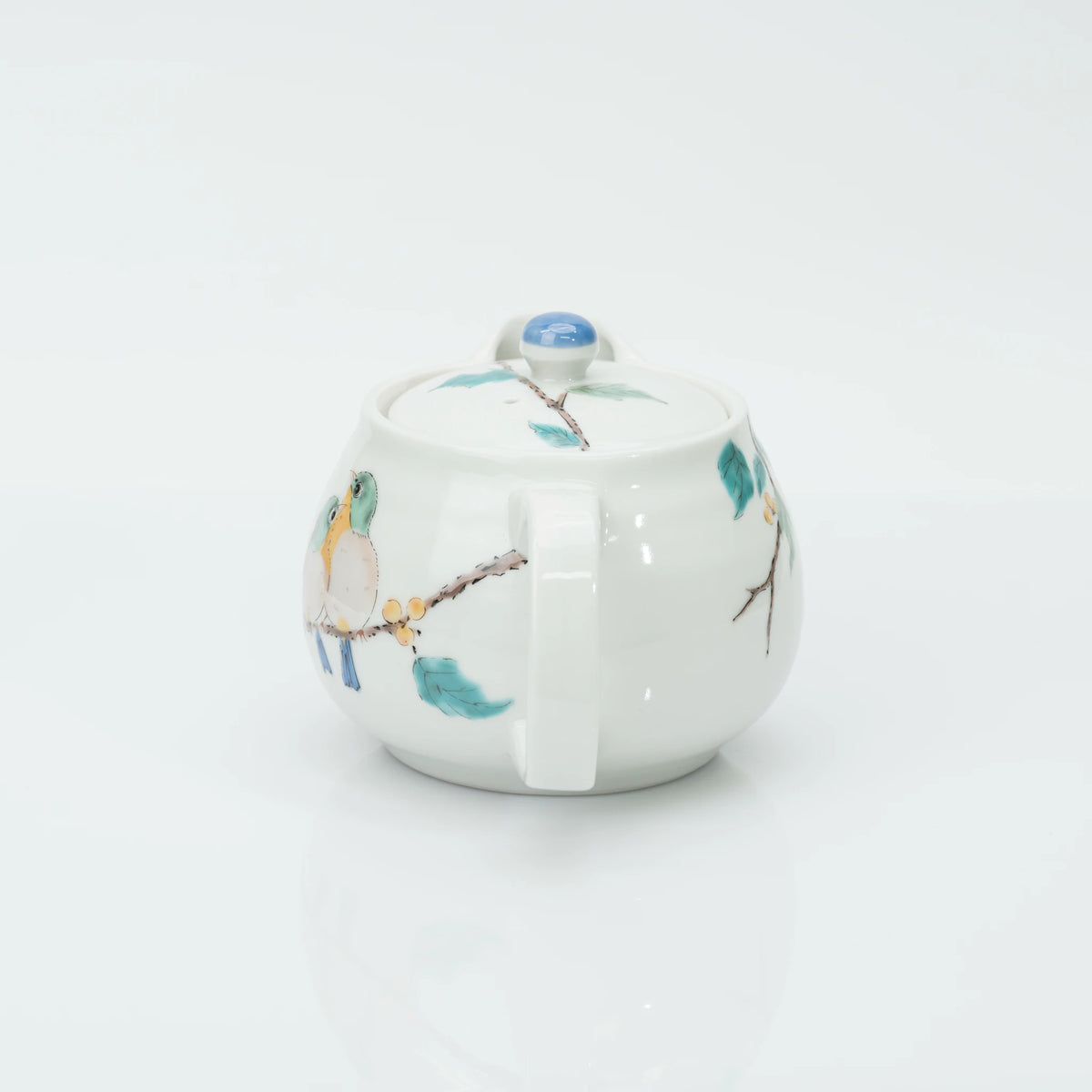 The Kutani teapot seen from behind, its loop handle and the berry branch carrying on around the body.