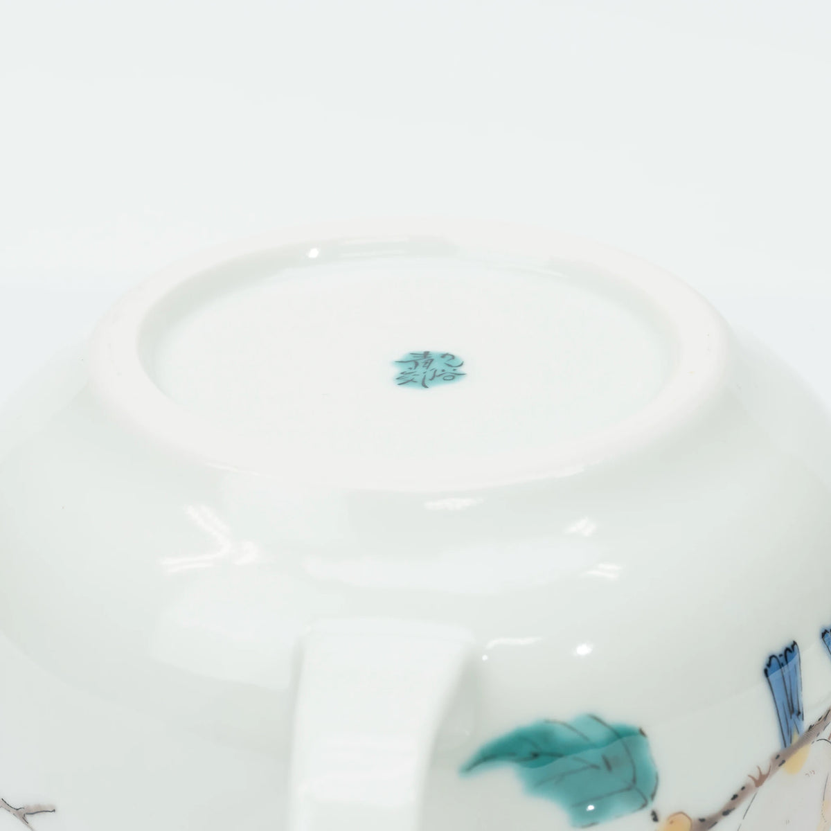 Underside of the teapot, the unglazed foot ring and the kiln's turquoise mark at the centre of the base.