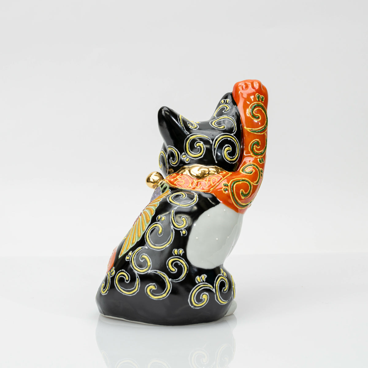 Back view showing the black ground with raised scrolling patterns and the gold-coloured bell