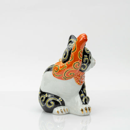 Side view showing the white porcelain body, black markings and gold-tipped paws