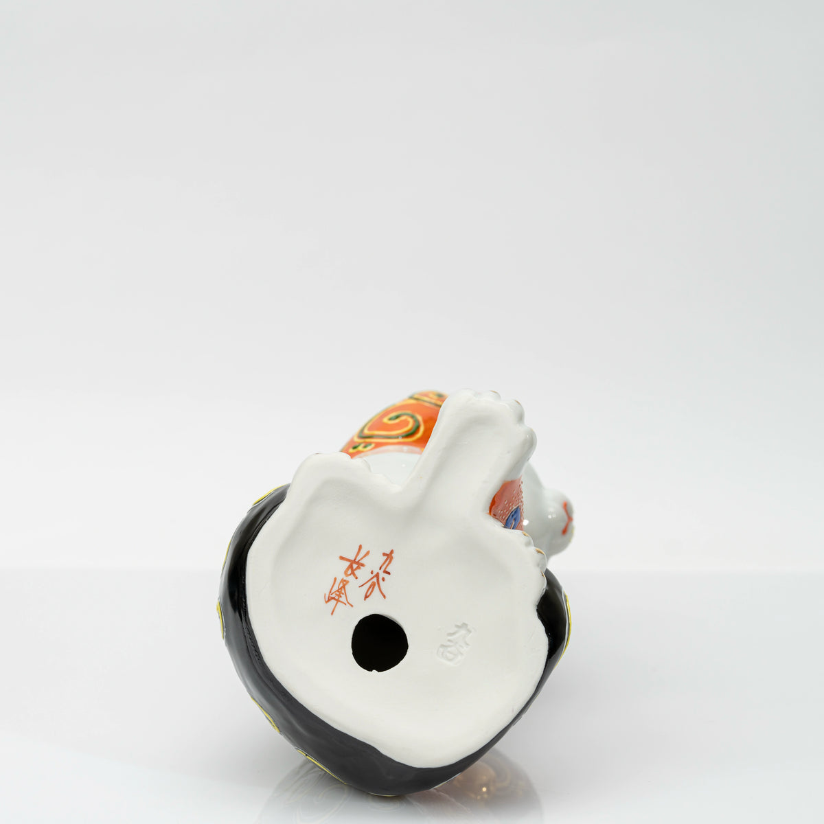 Base of the figurine with a red brushed mark, impressed 九谷 mark and firing vent