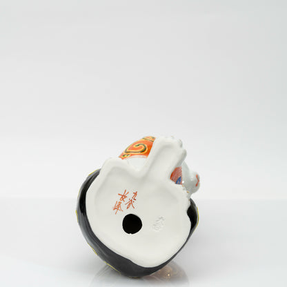 Base of the figurine with a red brushed mark, impressed 九谷 mark and firing vent