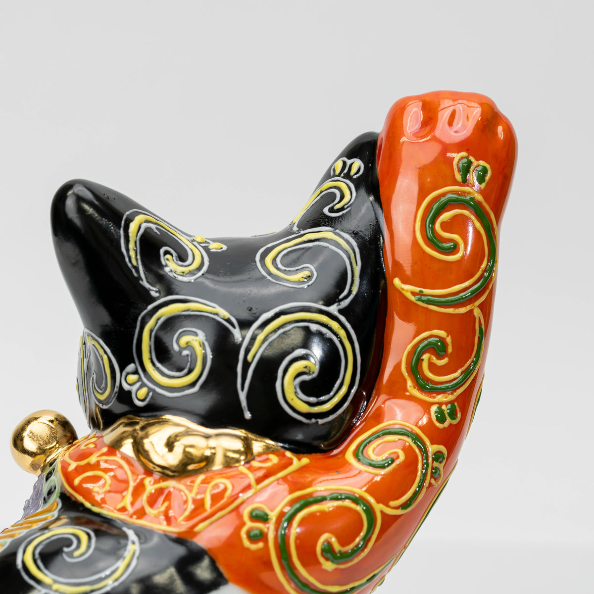 Close-up of the head and raised right paw with green and gold scrolling
