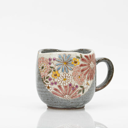 Red Kutani mug with a bouquet of red, pink, blue, yellow and white flowers and purple accents on a cream panel