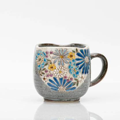 Blue Kutani mug with a bouquet of blue, yellow and white flowers and purple accents on a cream panel