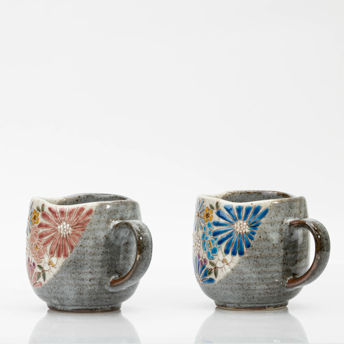 Side views of two Kutani mugs showing the grey glaze, handles and edges of the floral panels