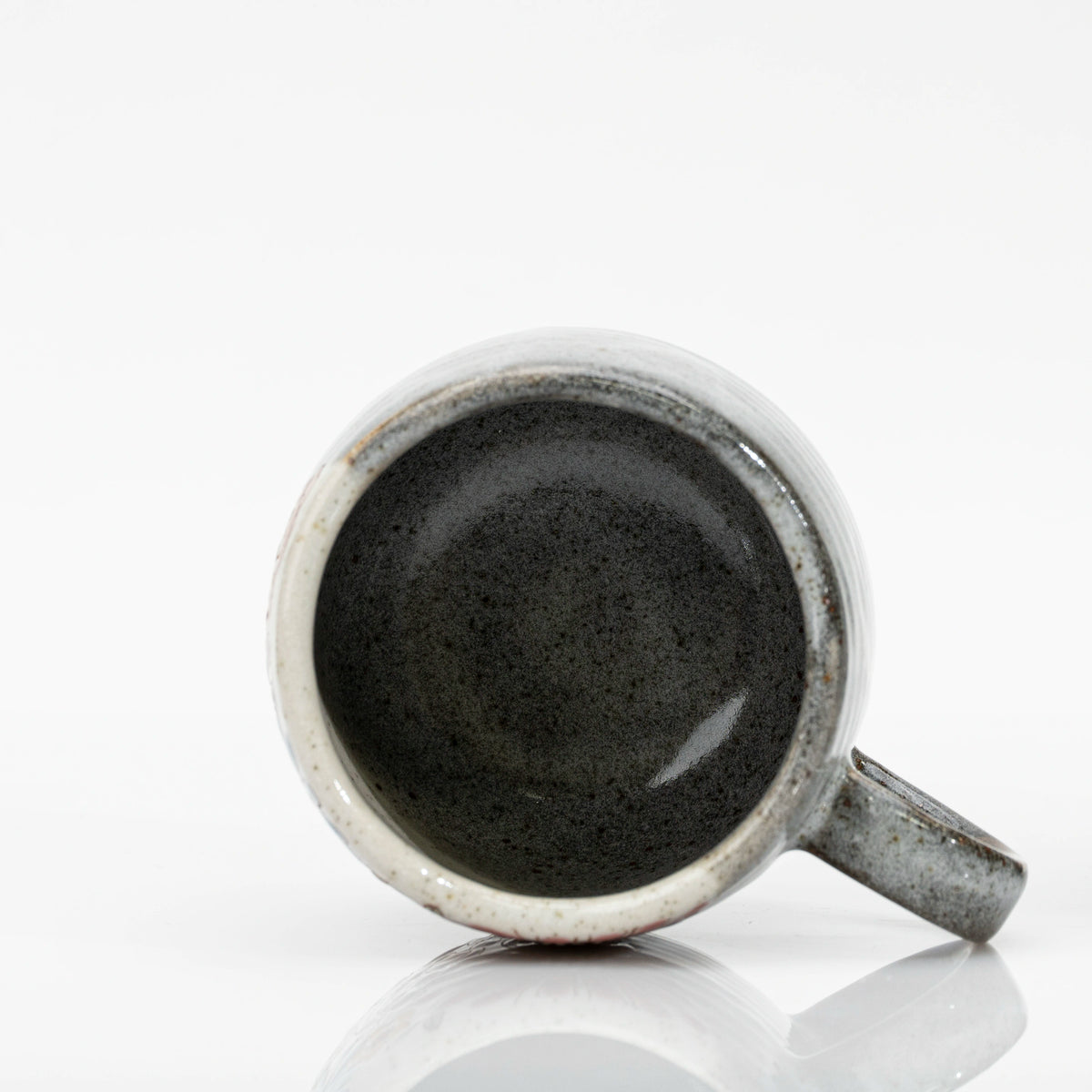 Top-down view inside a Kutani mug, glazed in dark speckled grey with a cream section at the rim