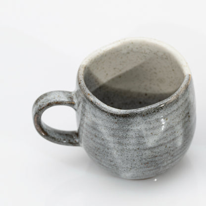 Kutani mug tilted to show the plain grey back and the glazed interior