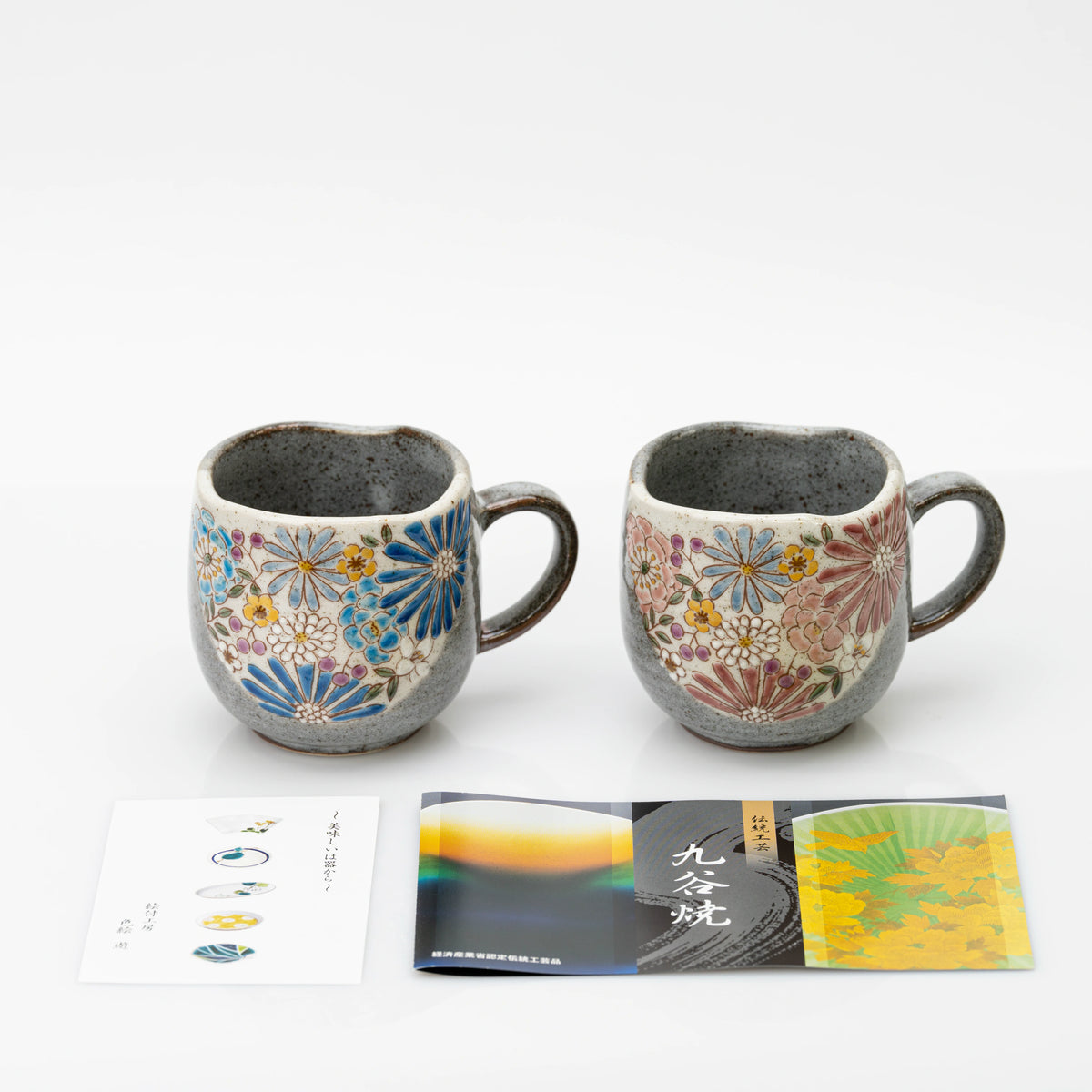 The red and blue Kutani mugs with printed leaflets laid in front