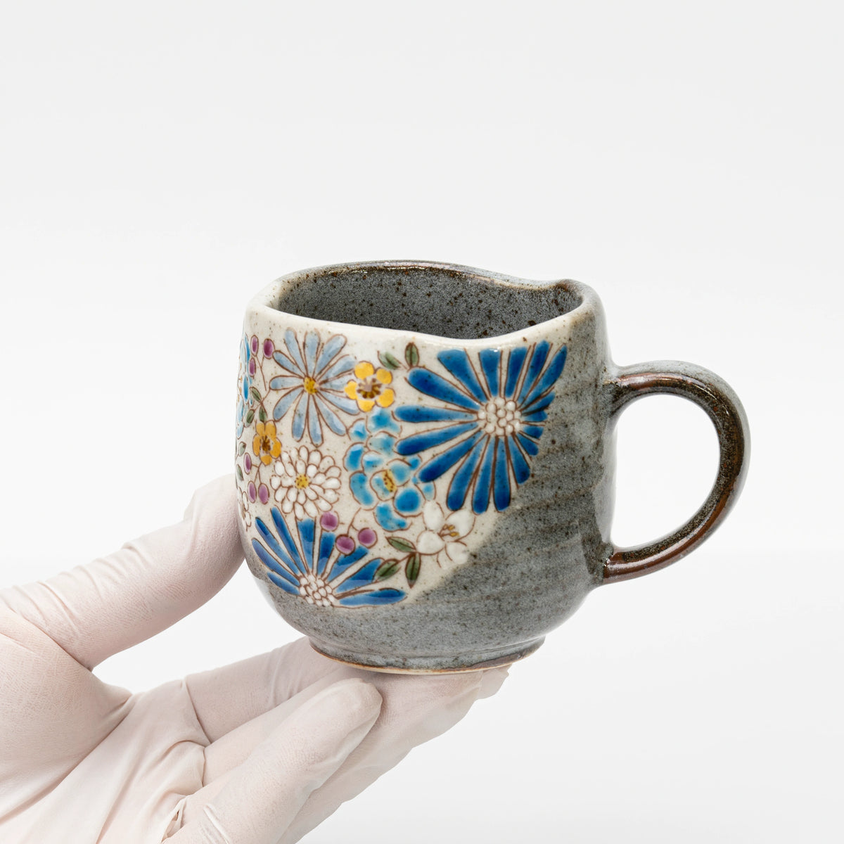 Blue Kutani mug held in a gloved hand to show its size
