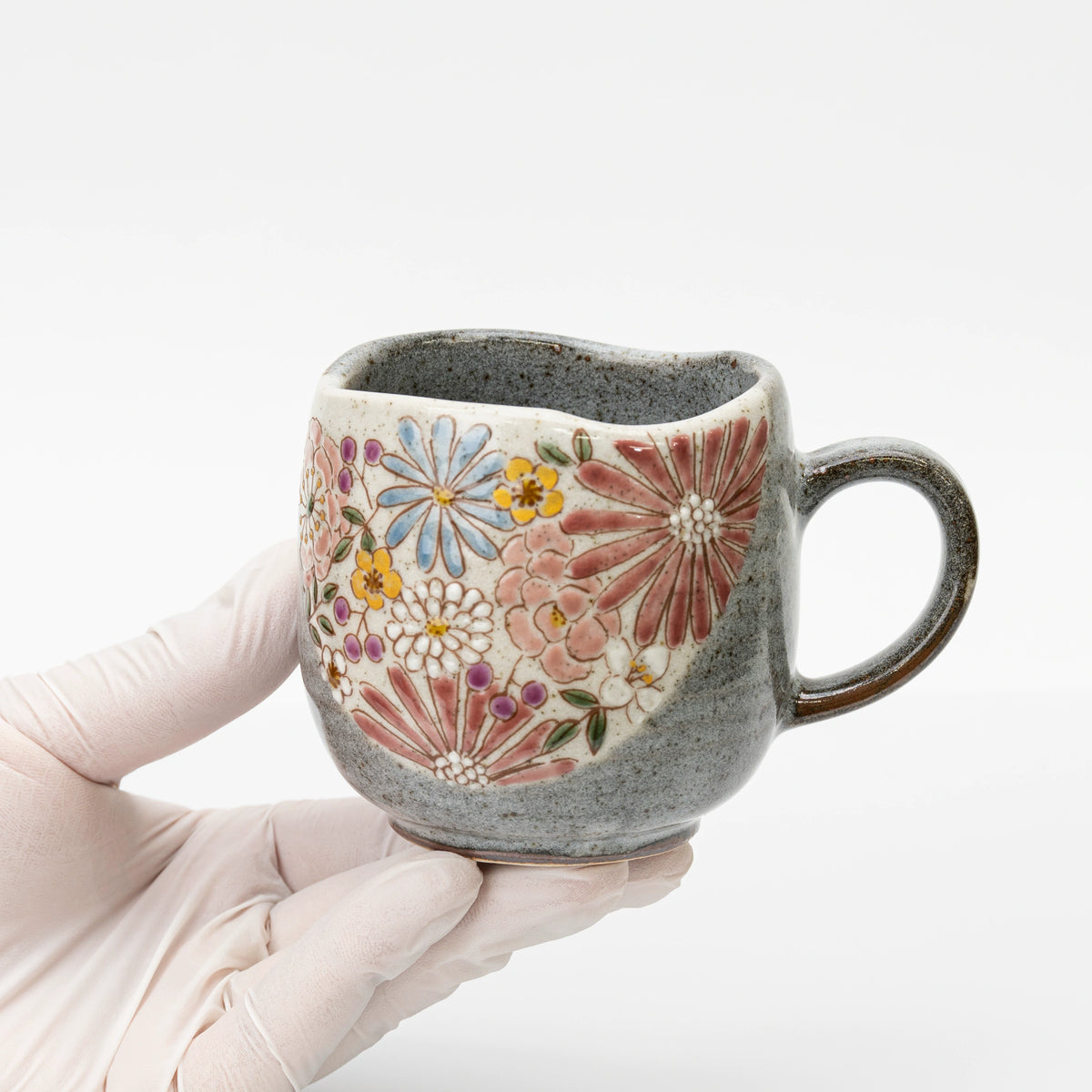 Red Kutani mug held in a gloved hand to show its size