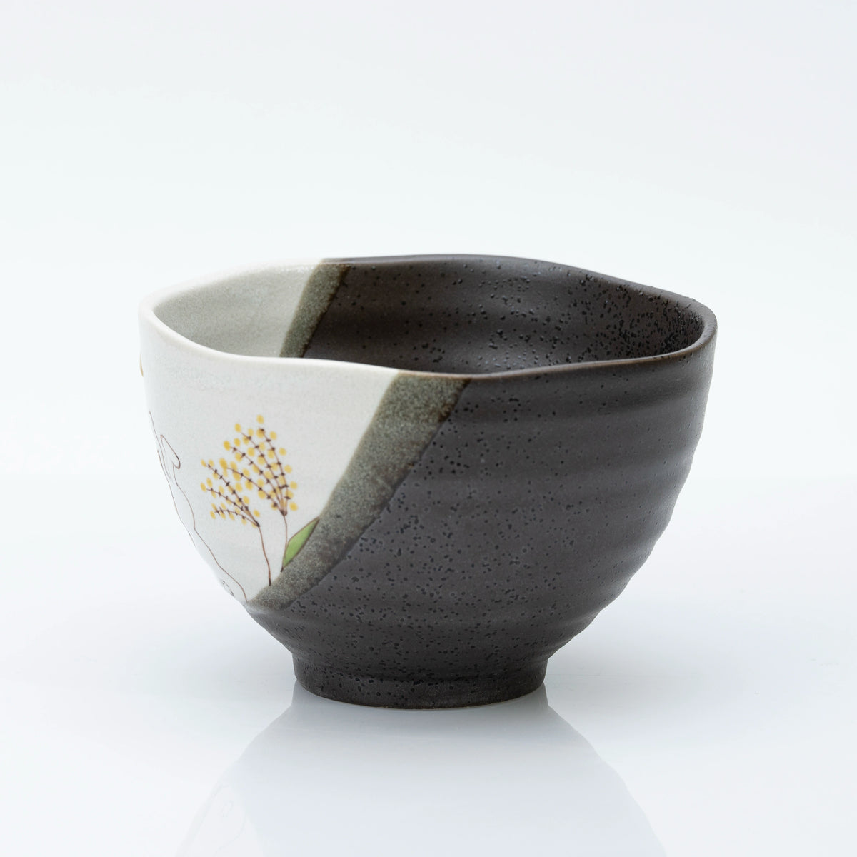 Side of the bowl where the cream panel meets the dark speckled glaze