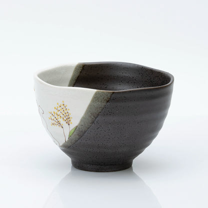 Side of the bowl where the cream panel meets the dark speckled glaze