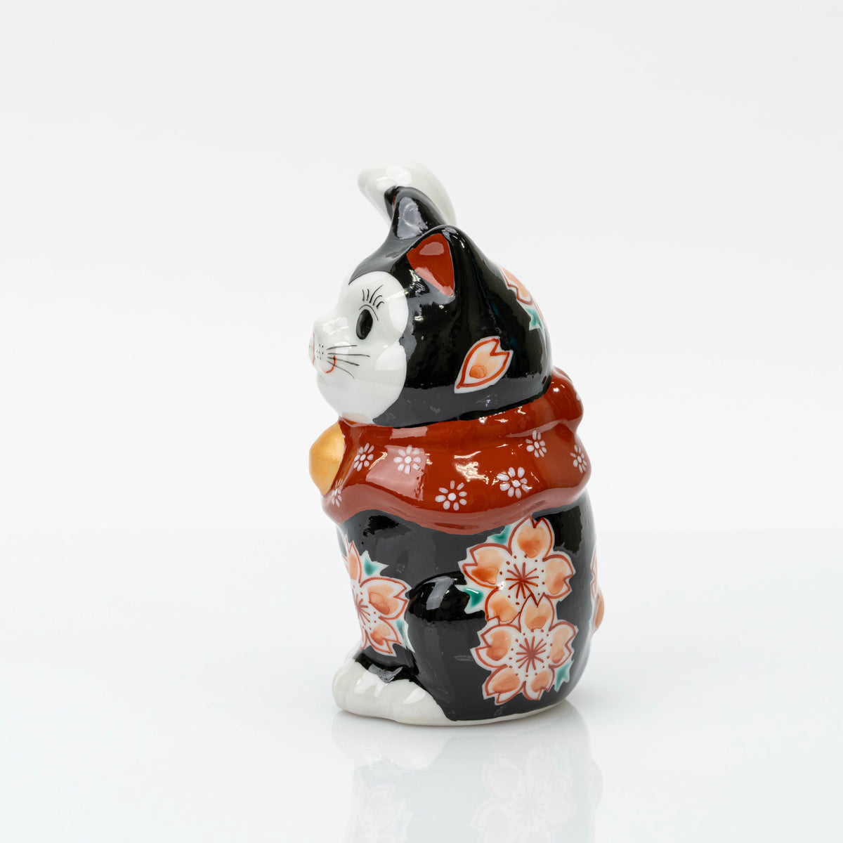 Side view of the black lucky cat with cherry blossoms along its body and raised paw