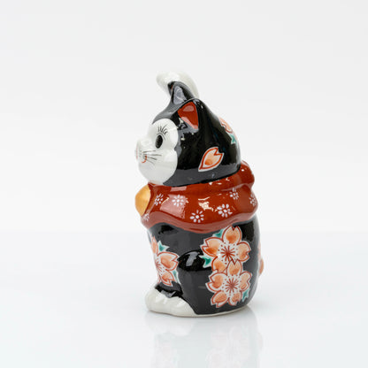 Side view of the black lucky cat with cherry blossoms along its body and raised paw