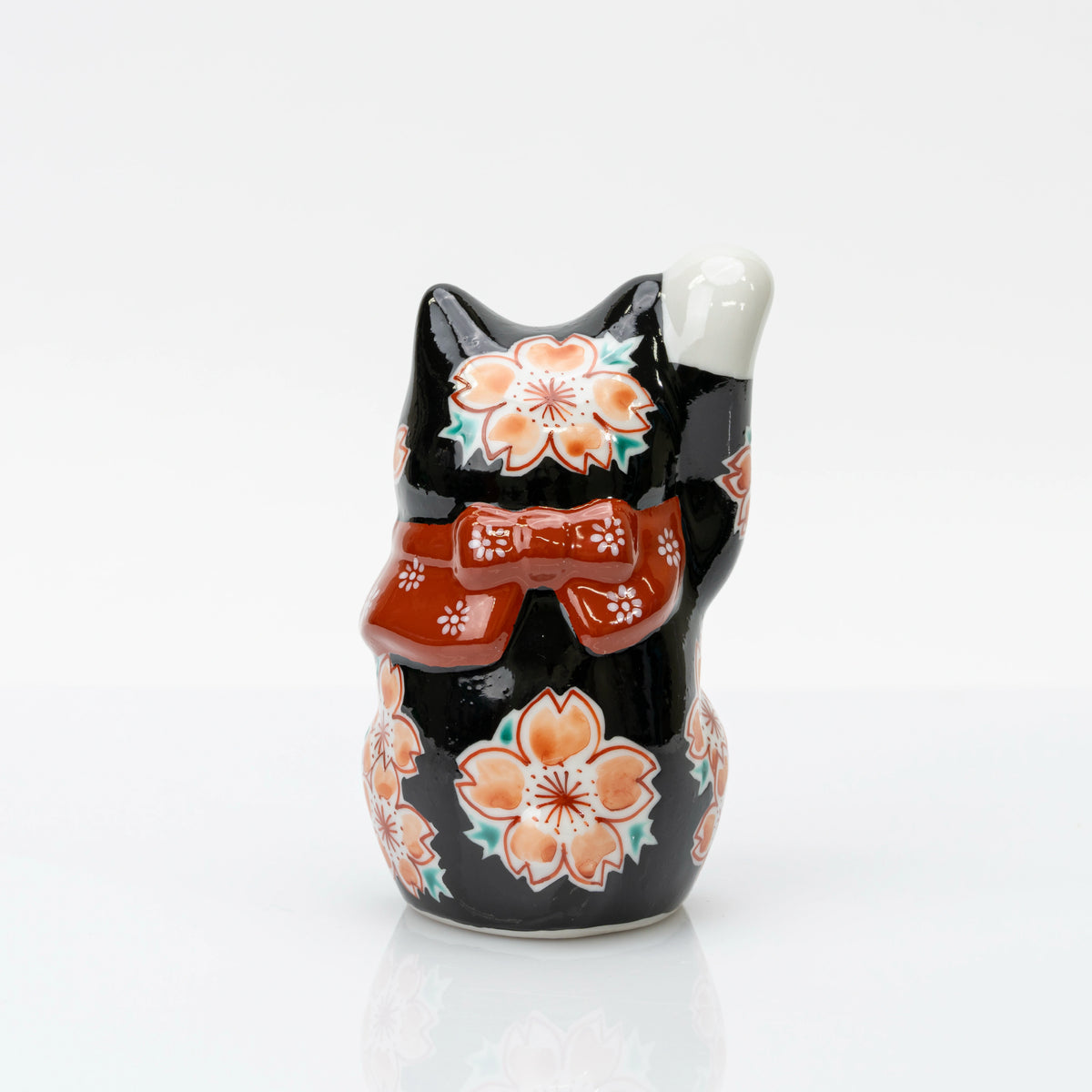 Back view of the black Kutani lucky cat with cherry blossoms and a red bow