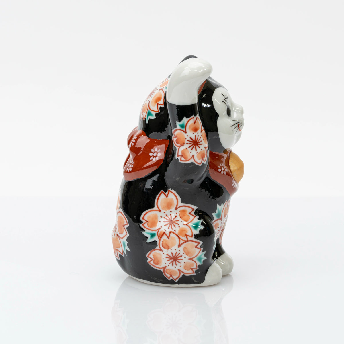 Opposite side of the black lucky cat showing blossoms along its body and raised paw