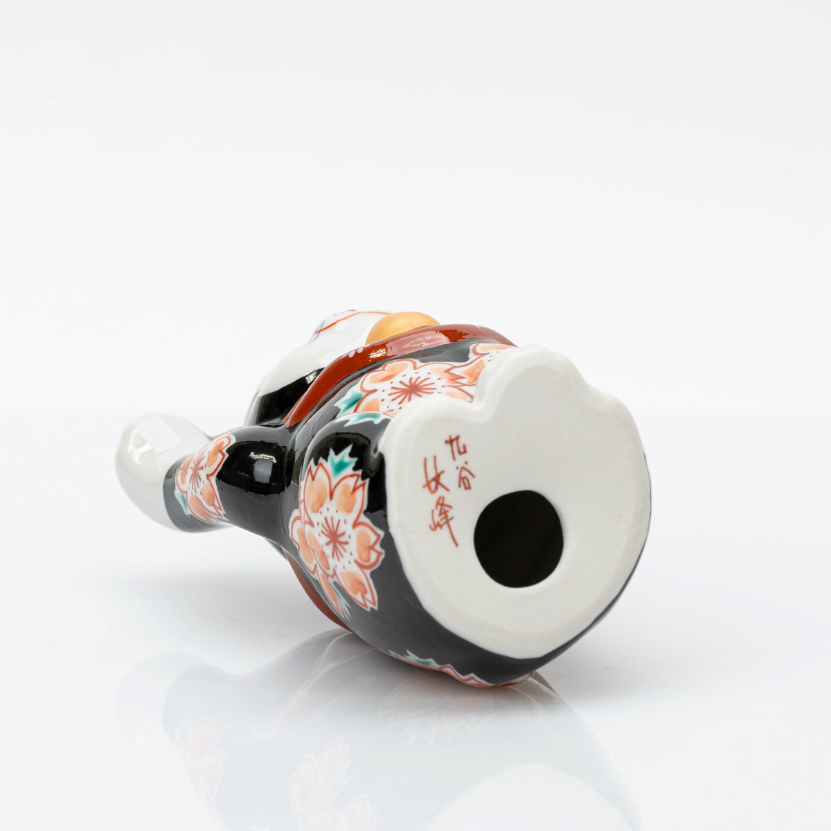Underside of the Kutani lucky cat with a small vent hole and red maker's mark
