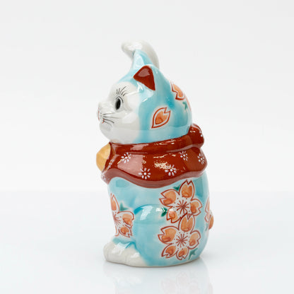 Side view of turquoise blue maneki neko with cherry blossoms and a red floral bib