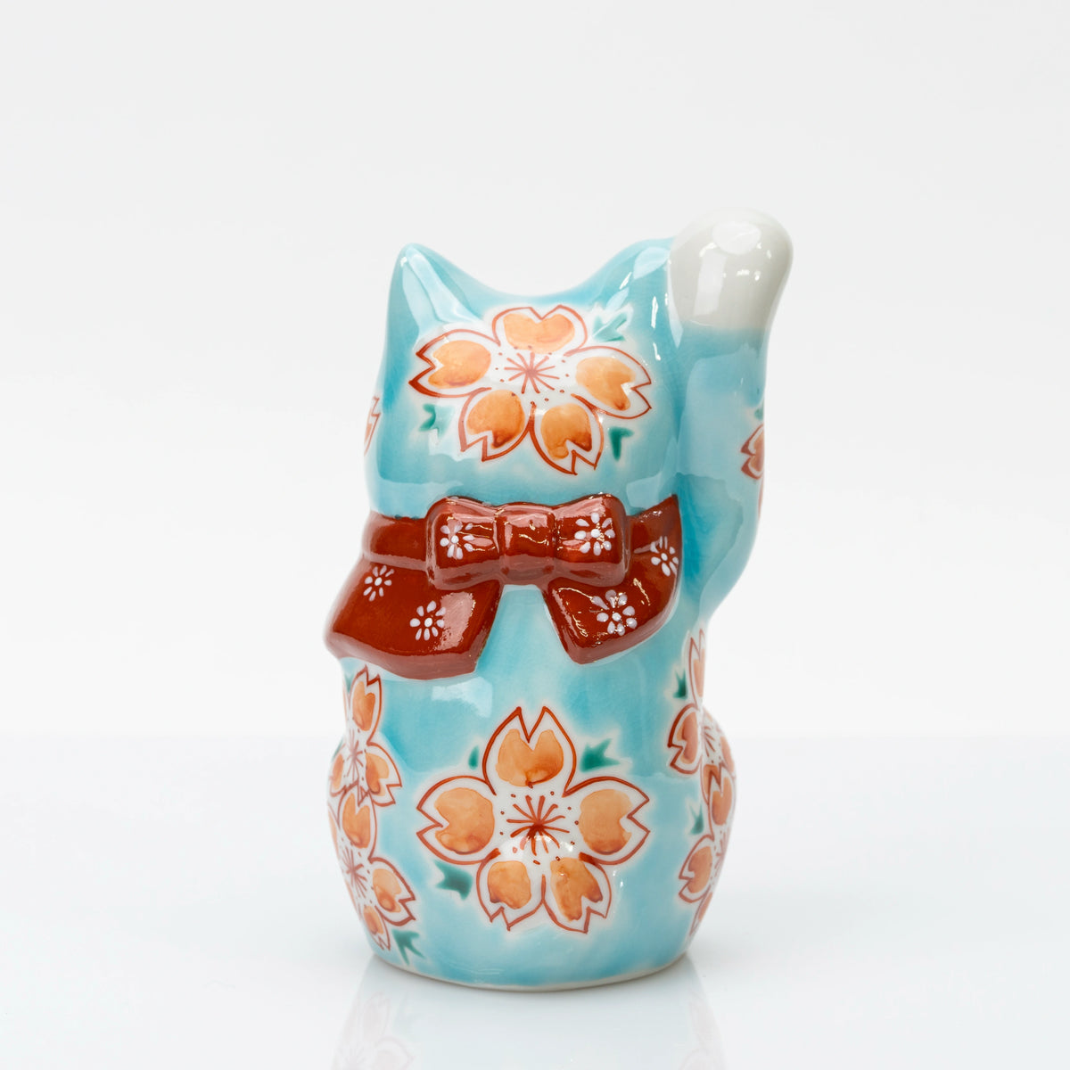 Back view of turquoise blue lucky cat with cherry blossoms and a red bow