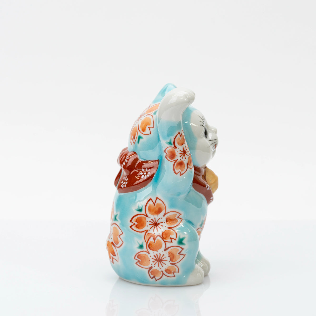 Opposite side of blue lucky cat showing blossoms along the body and raised paw