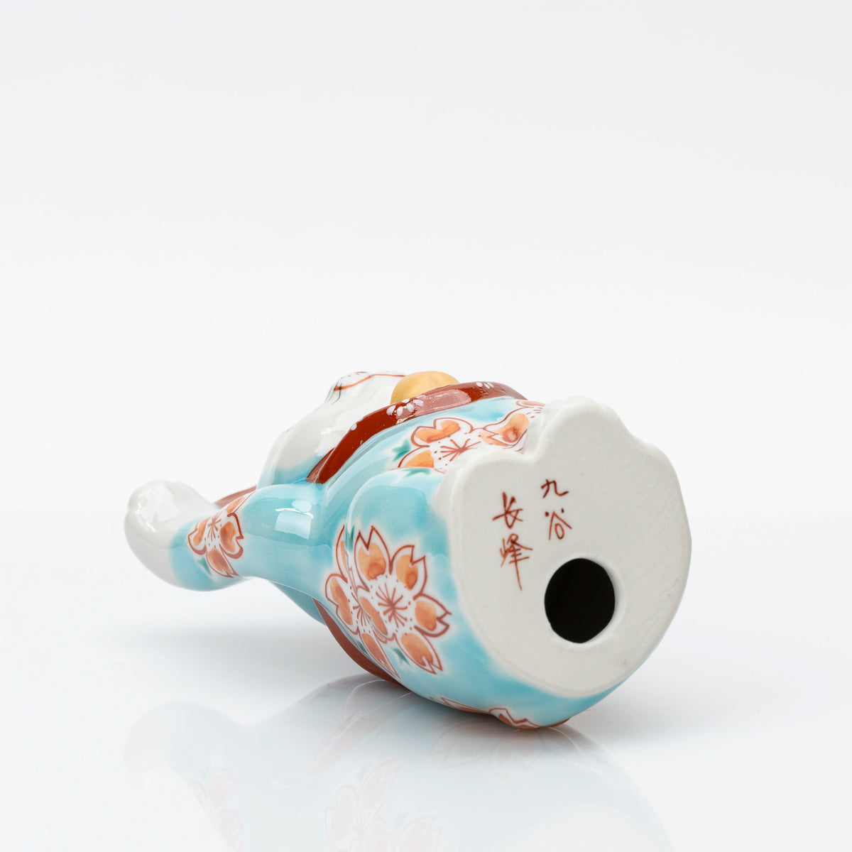 Underside of Kutani lucky cat showing the red Chōhō mark and vent hole