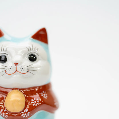 Close-up of the lucky cat's white face, black eyes, and red inner ears