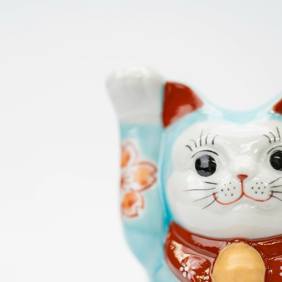 Close-up of the raised paw, white face, and turquoise blue glaze