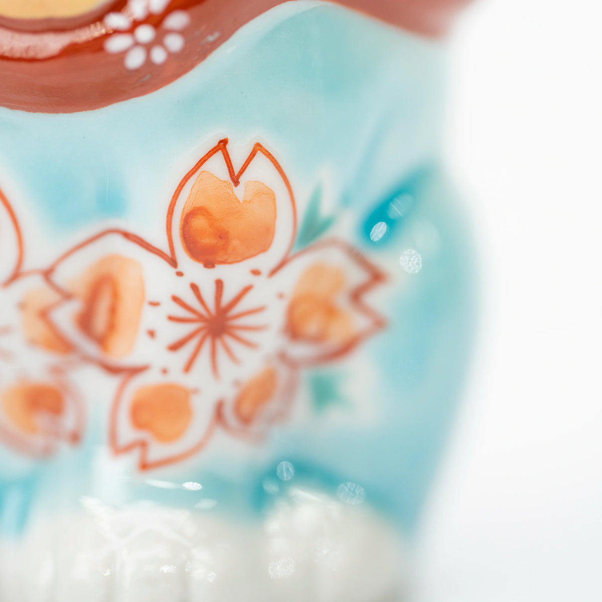 Close-up of peach-toned cherry blossoms against the turquoise blue glaze